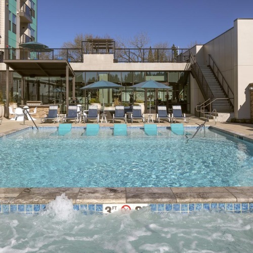 a pool with chairs and umbrellas by a building