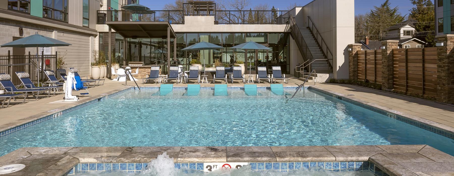 a pool with chairs and umbrellas by a building